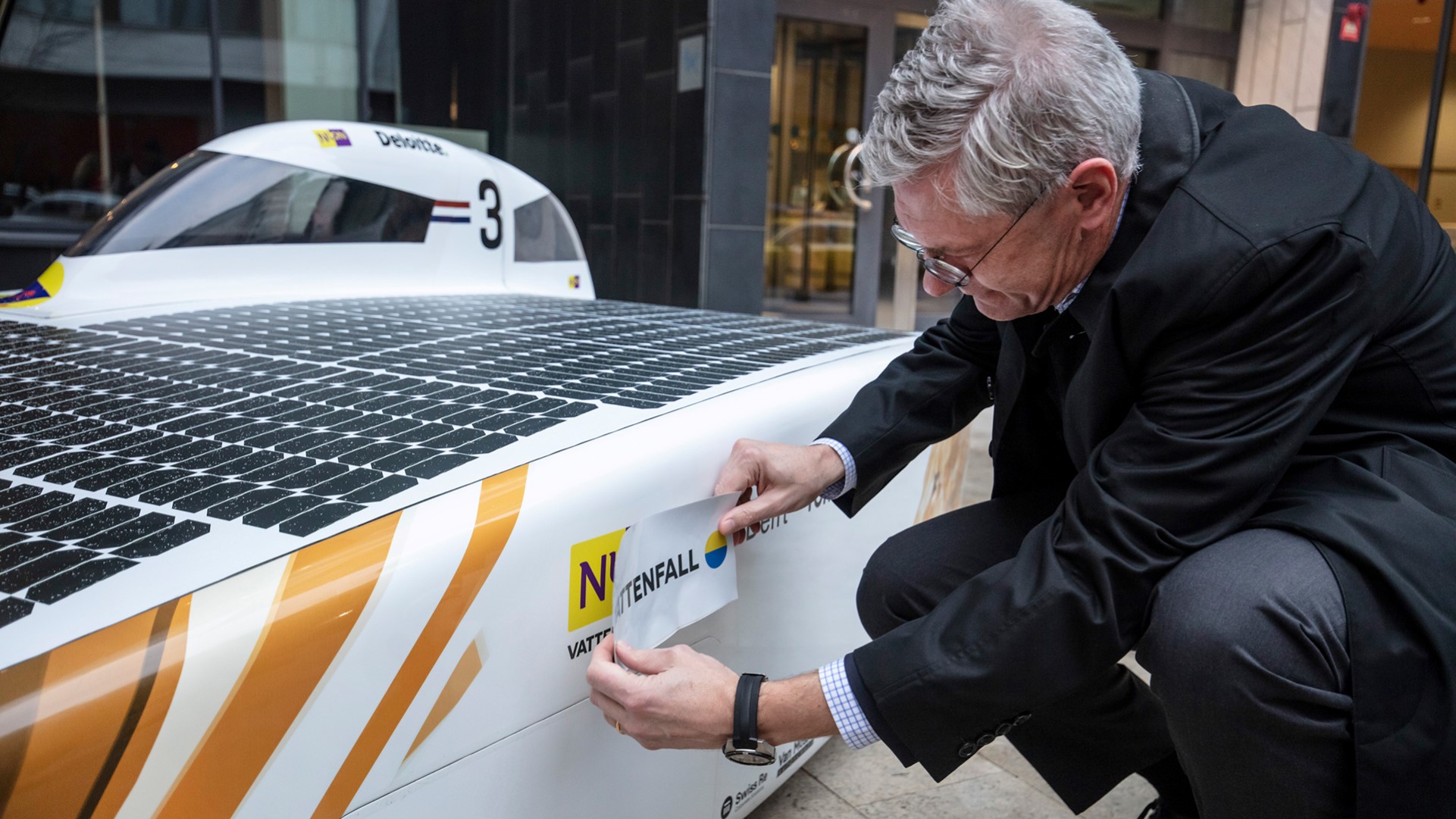 Magnus Hall klebt Vattenfall-Logo an das Nuon-Solarmobil
