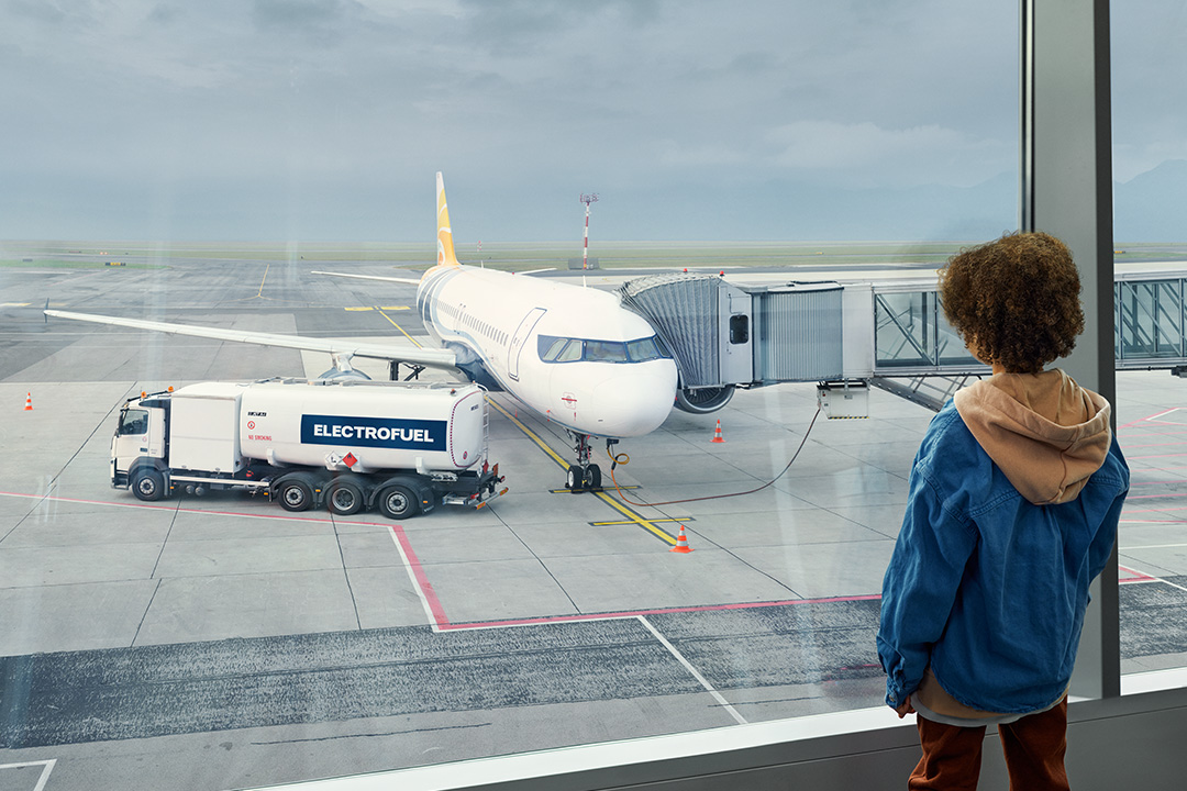 Junge schaut auf Flughafen aus einem Fenster und betrachtet Flugzeug