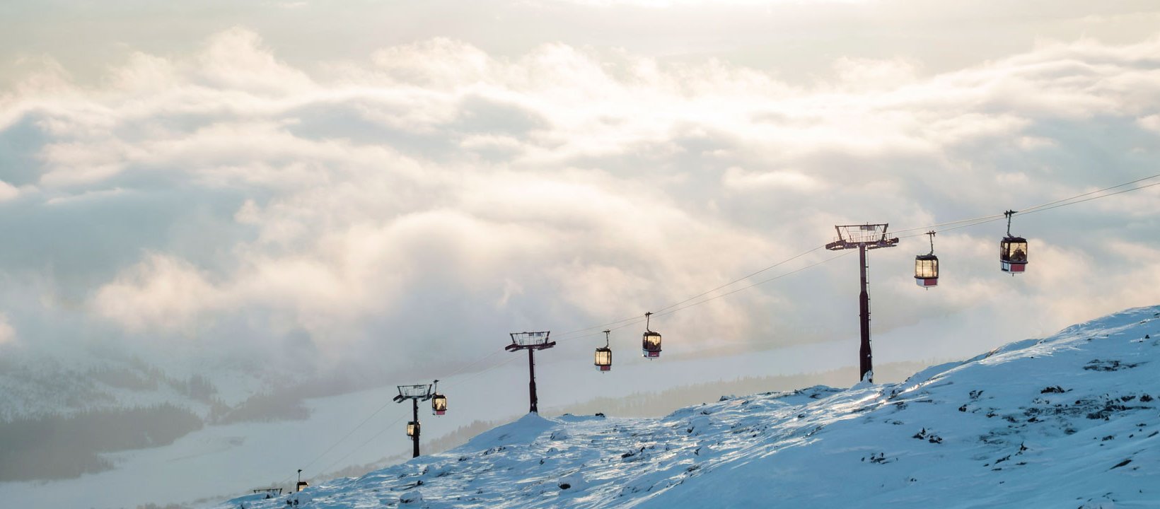 Skilift med bjerge og skyer i baggrunden