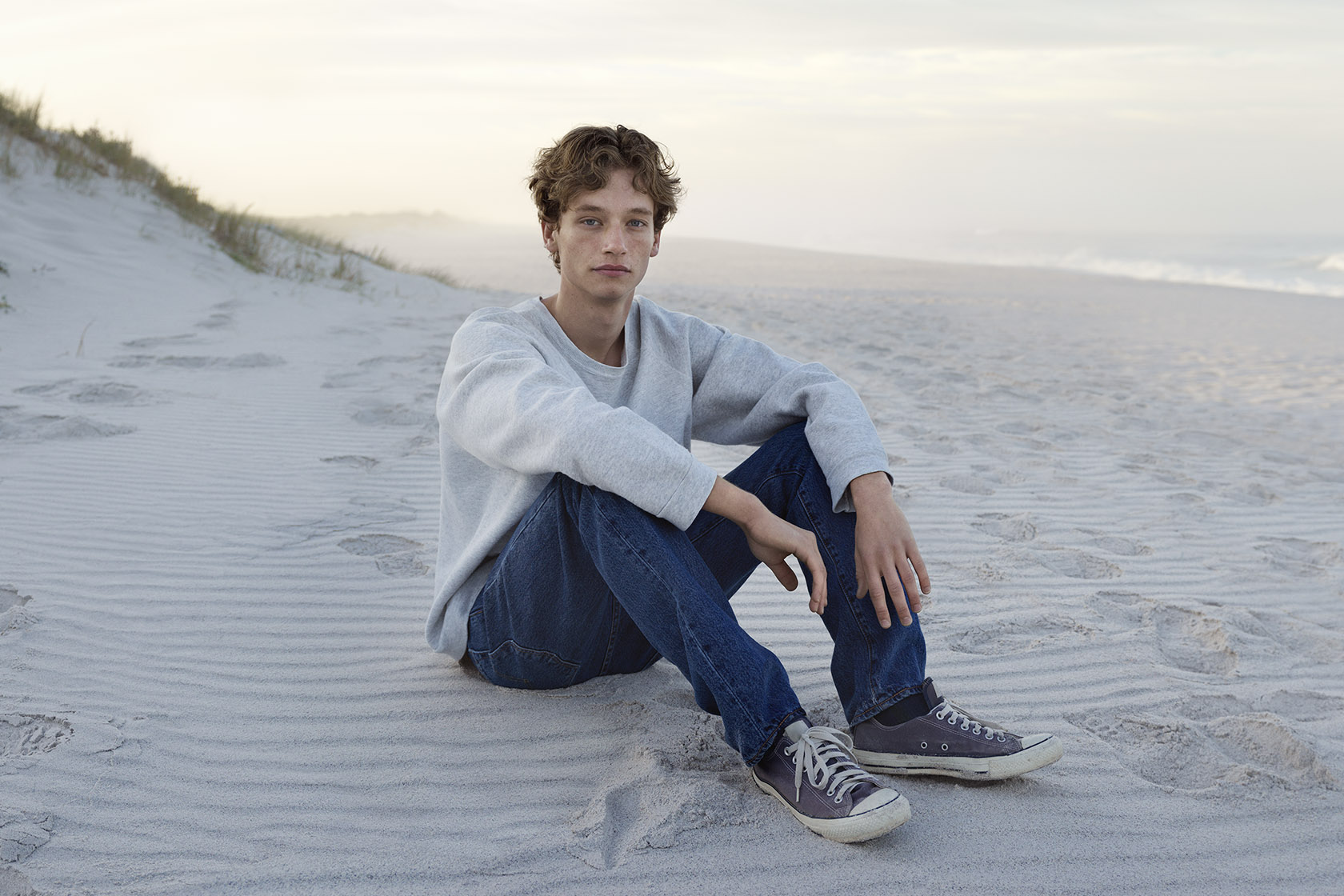 Teenagedreng, der sidder på en strand Teenagedreng, der sidder på en strand