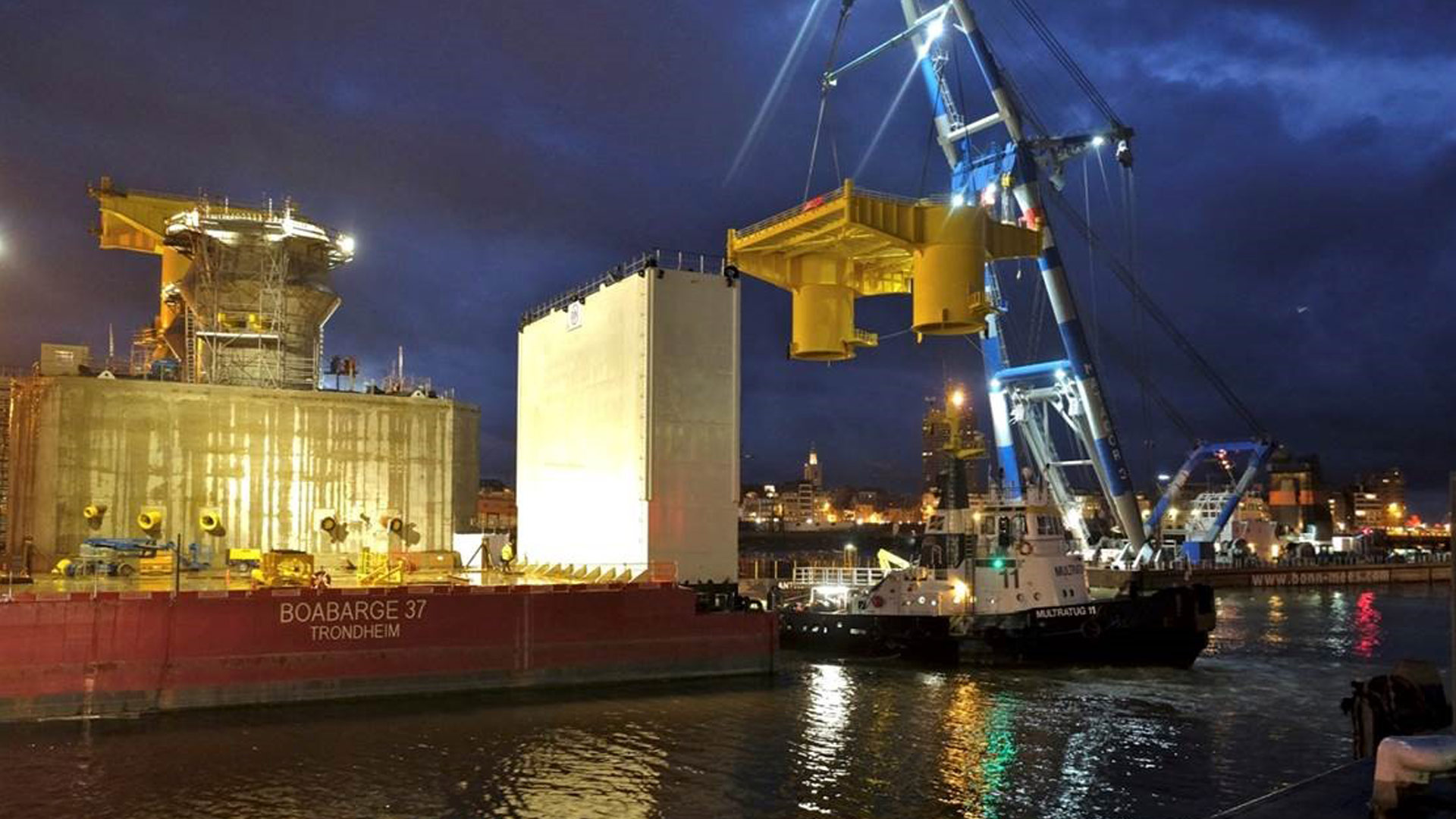 På havnen i Ostende i Belgien blev fundamenterne og overgangsstykkerne til platformene samlet før afskibningen. Her bliver stålkonstruktionen til den største af platformene løftet på plads. Foto: Jan de Nul Group