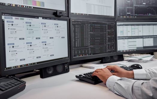 Lähikuva miehen käsistä tietokoneen näppäimistöllä useiden näyttöjen edessä Vattenfallin kauppatoimistossa Hampurissa.