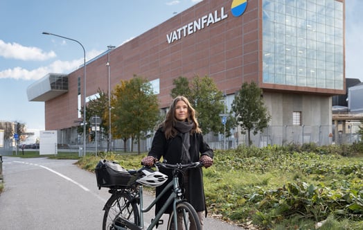 Une femme avec un vélo devant une centrale thermique