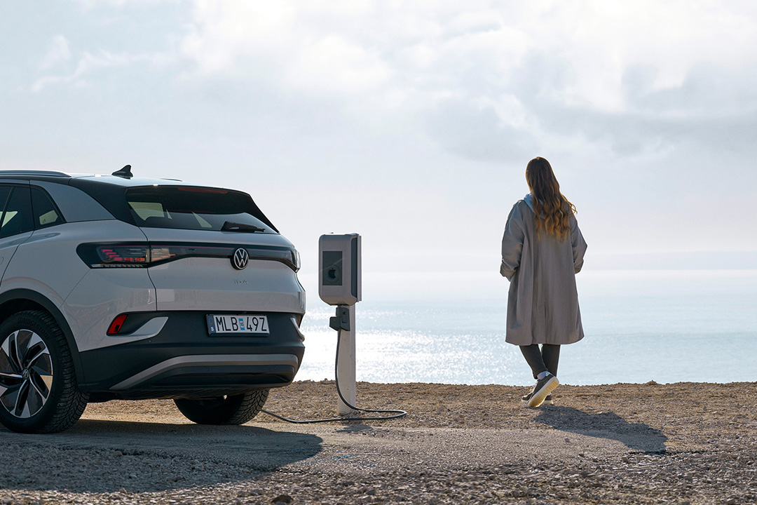 Une femme à côté d'une voiture électrique Une femme à côté d'une voiture électrique