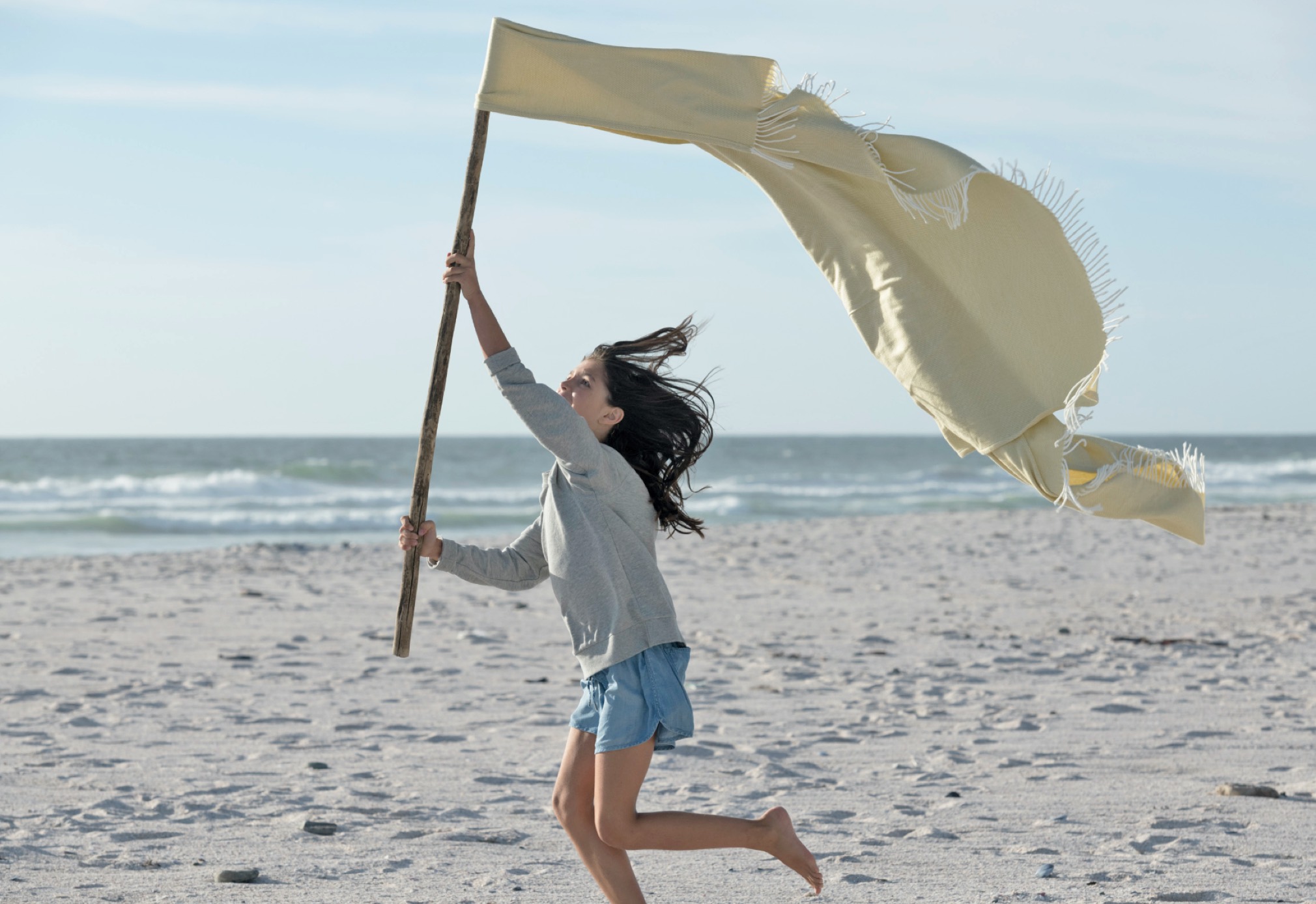 Girl with a stick running on the beach  /Mädchen mit Stofftuch am Stock über Strand laufend