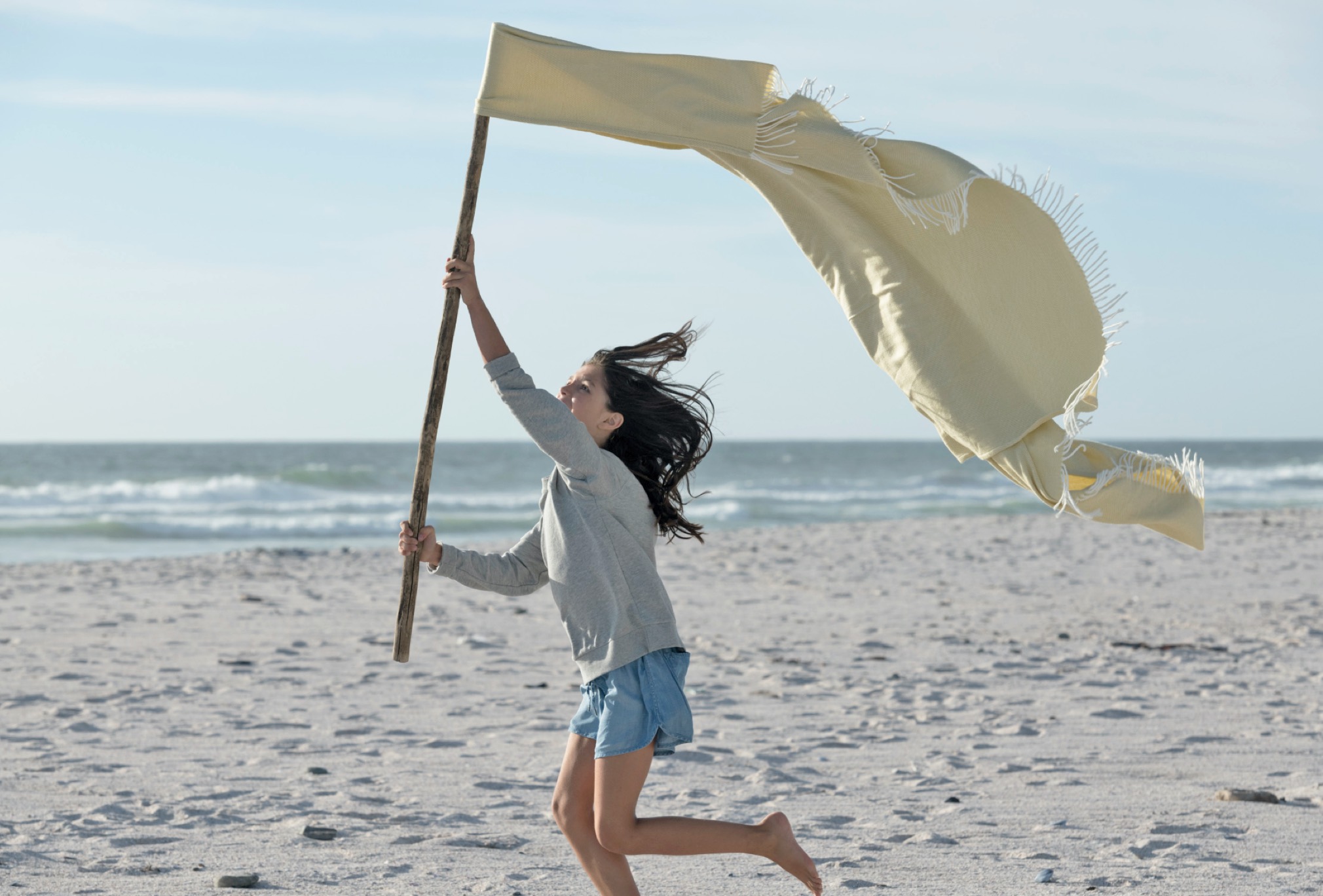 Girl with a stick running on the beach  / Mädchen mit Stofftuch am Stock über Strand laufend