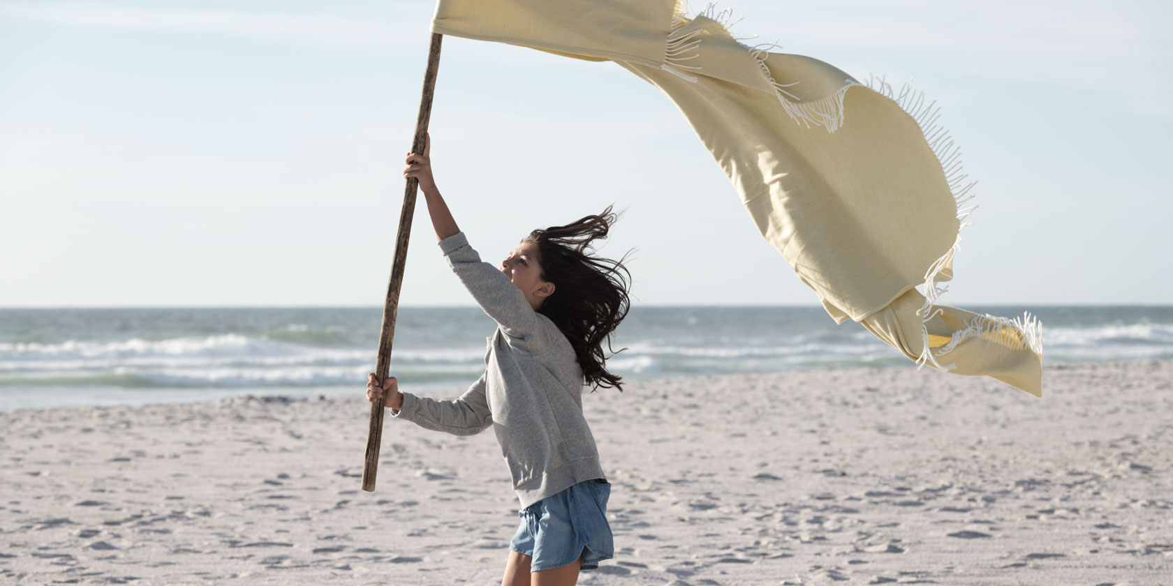 A girl running on a beach with a flag