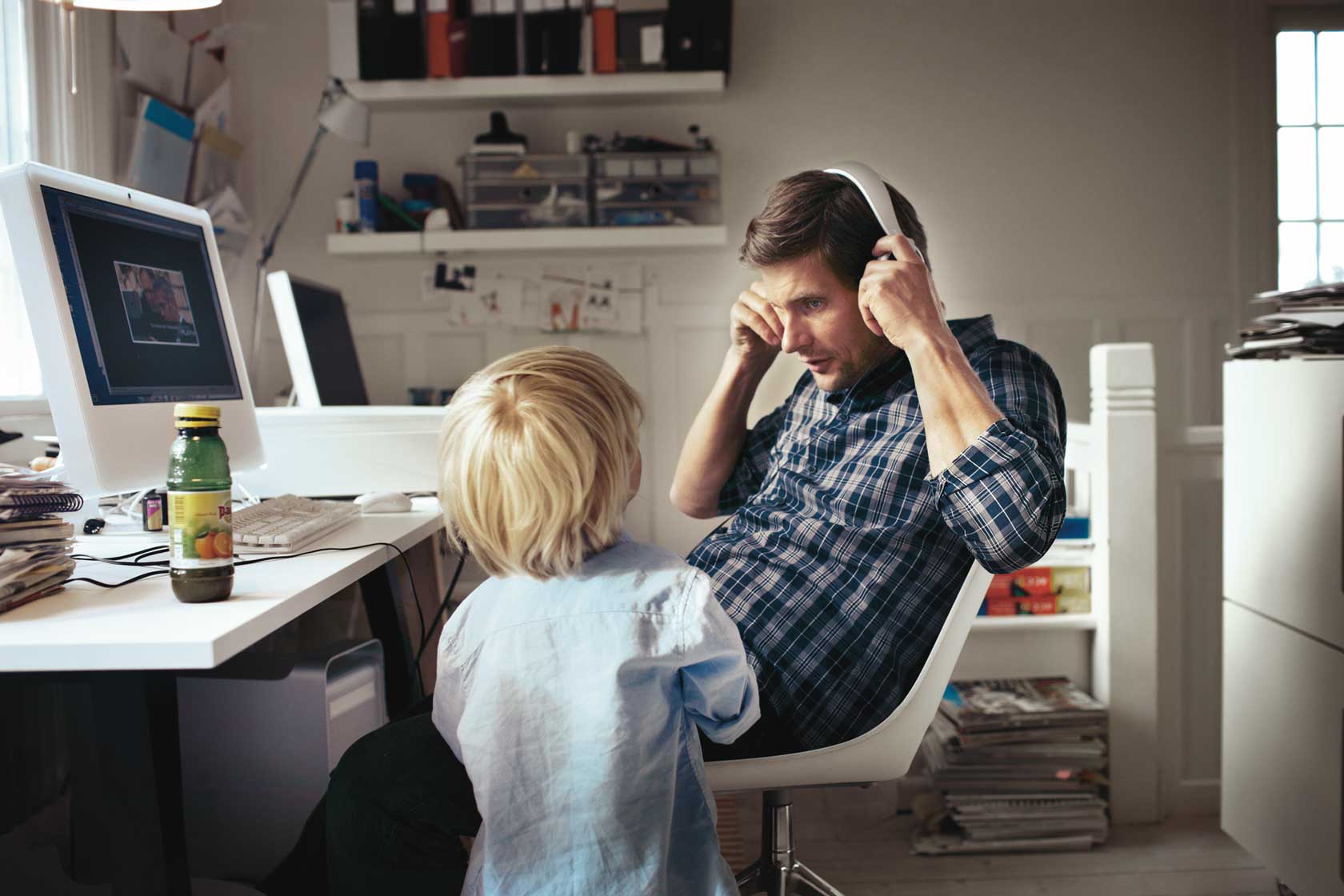 A child and a man by a computer in an office