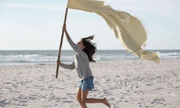 En flicka som springer med en flagga på en strand