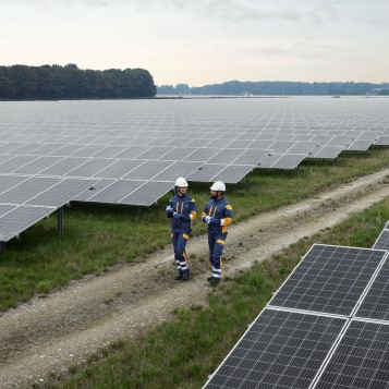 Two employees in protective clothing walking in a solar farm