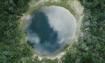 Bird's-eye view of a circular pond surrounded by trees