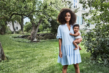 Frau mit Kind auf dem Arm im Garten stehend