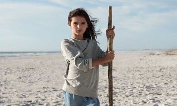Flicka med vandringsstav på en strand