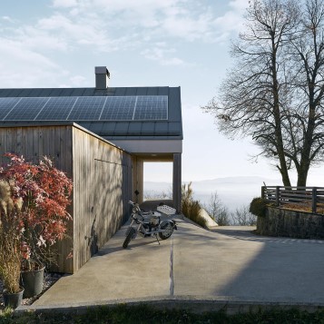 En elektrisk motorcykel foran et hus med solceller på taget