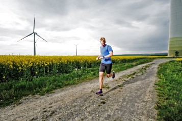 Läufer neben einer Windenergieanlage