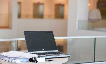 En bärbar dator och en hög med dokument på ett bord