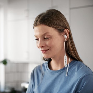 En kvinna som lyssnar i hörlurar