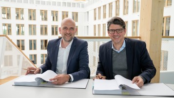 Martin Rodeck und Christian Barthélémy unterschreiben vor der Kulisse des Atriums den Mietvertrag