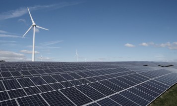 Image of solar panels in front of a wind turbine.