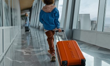Barn som drar en kabinväska av plast