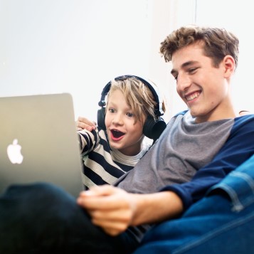 Två pojkar som sitter i en soffa och tittar på en bärbar dator