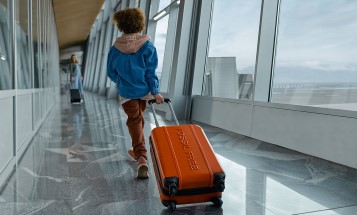 Junge auf Flughafen einen Koffer hinter sich herziehend Junge auf Flughafen einen Koffer hinter sich herziehend