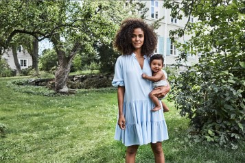 Frau mit Baby auf dem Arm im Garten stehend