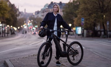 Woman with a bicycle standing on a street in Stockholm