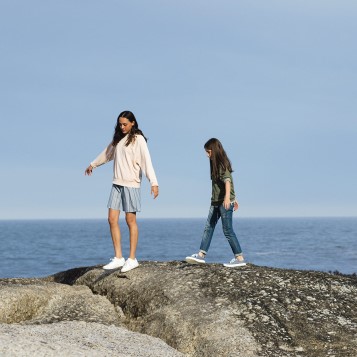 Zwei Mädchen über Felsen am Strand gehend