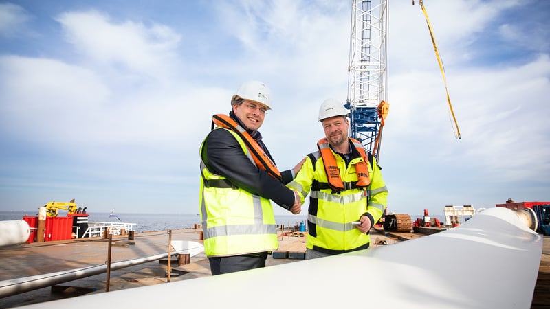 Robin van Buchem, Head of Operations NL bij Vattenfall, overhandigt een van de windturbinebladen aan Philip Mol, directievoorzitter MBO College Airport