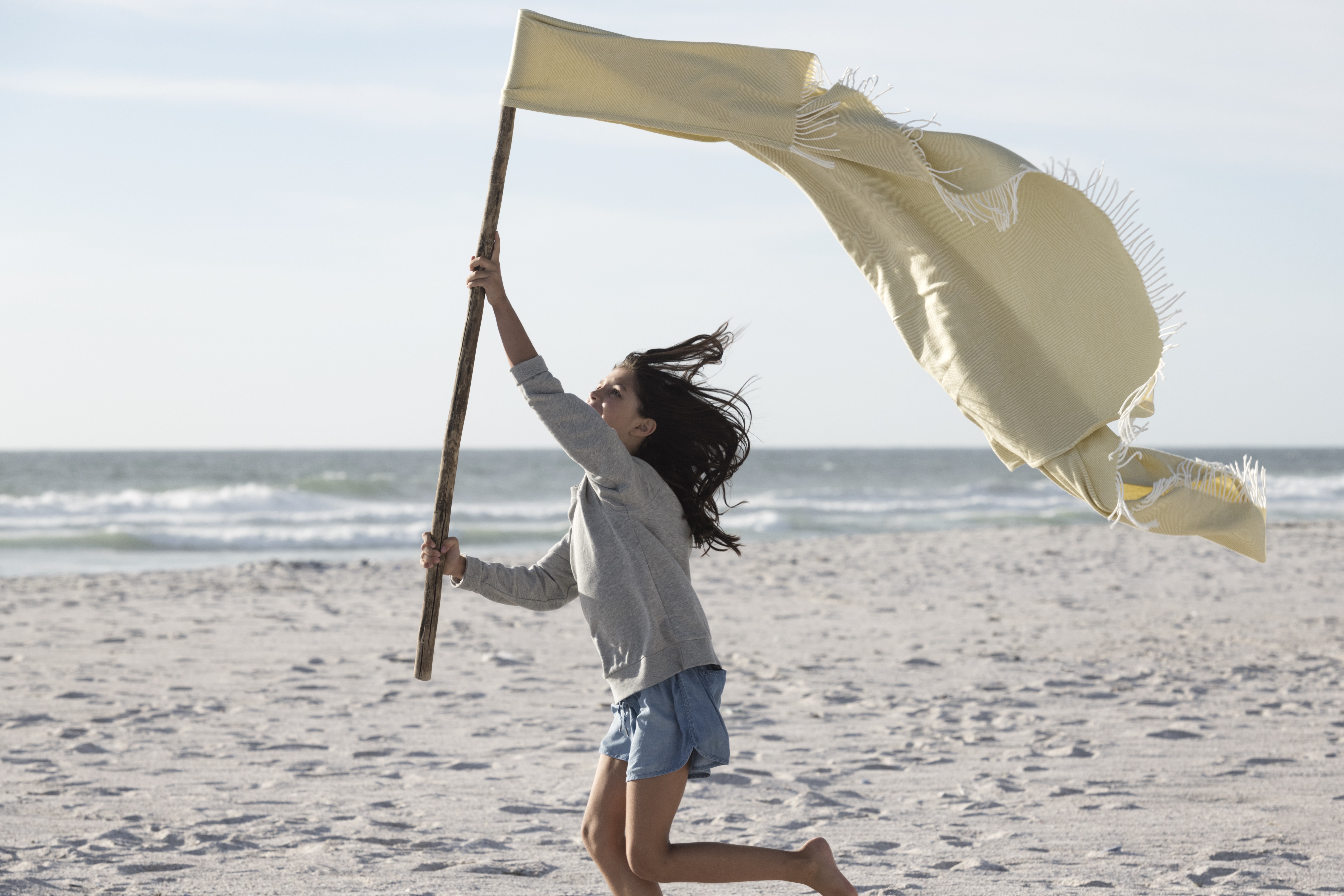 Girl on a beach running with a flag