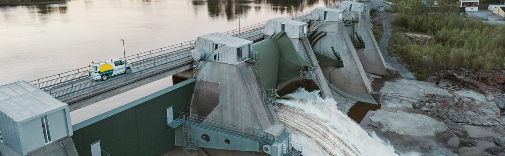 En bil från Vattenfall åker ovanför dammluckorna i ett vattenkraftverk.