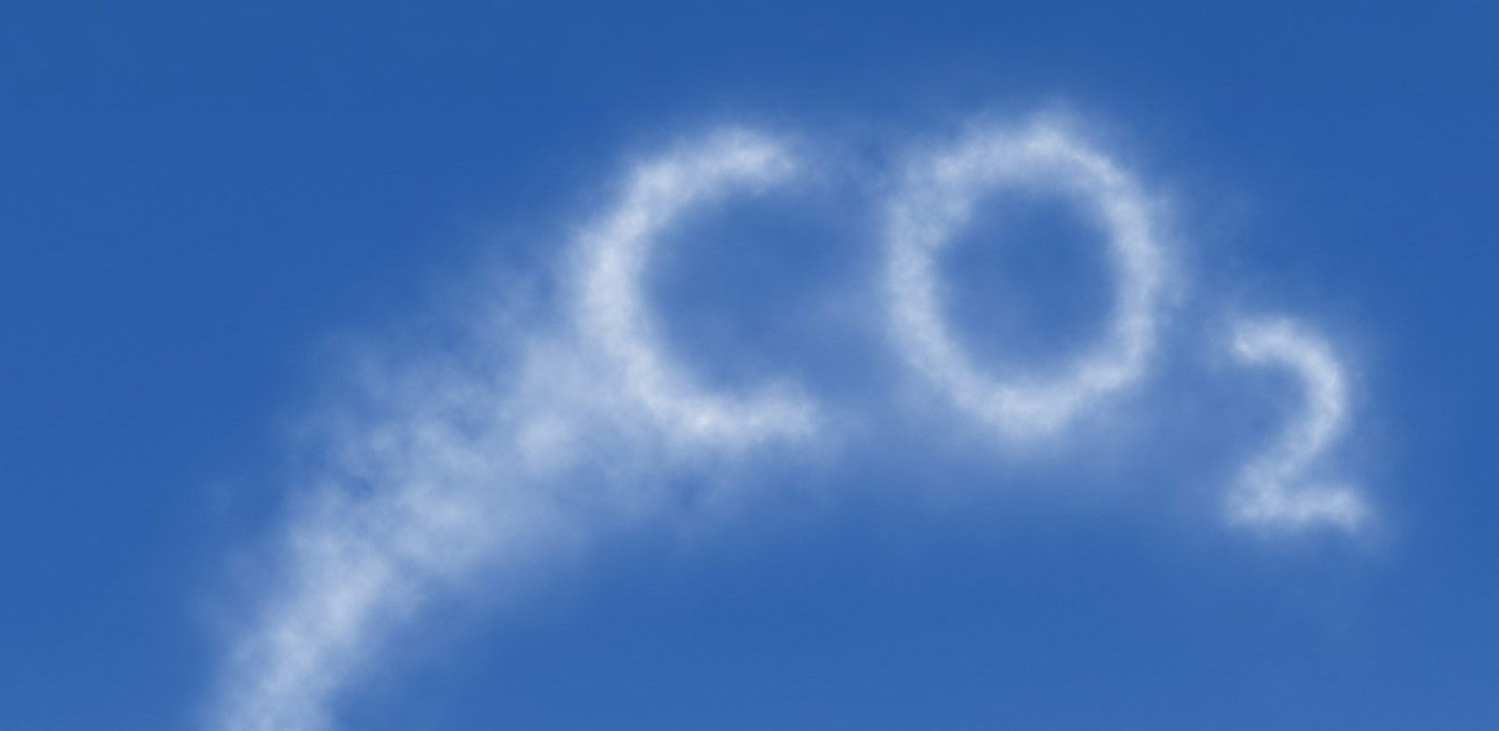 Vit rök som formar texten ”CO2” mot klarblå himmel.