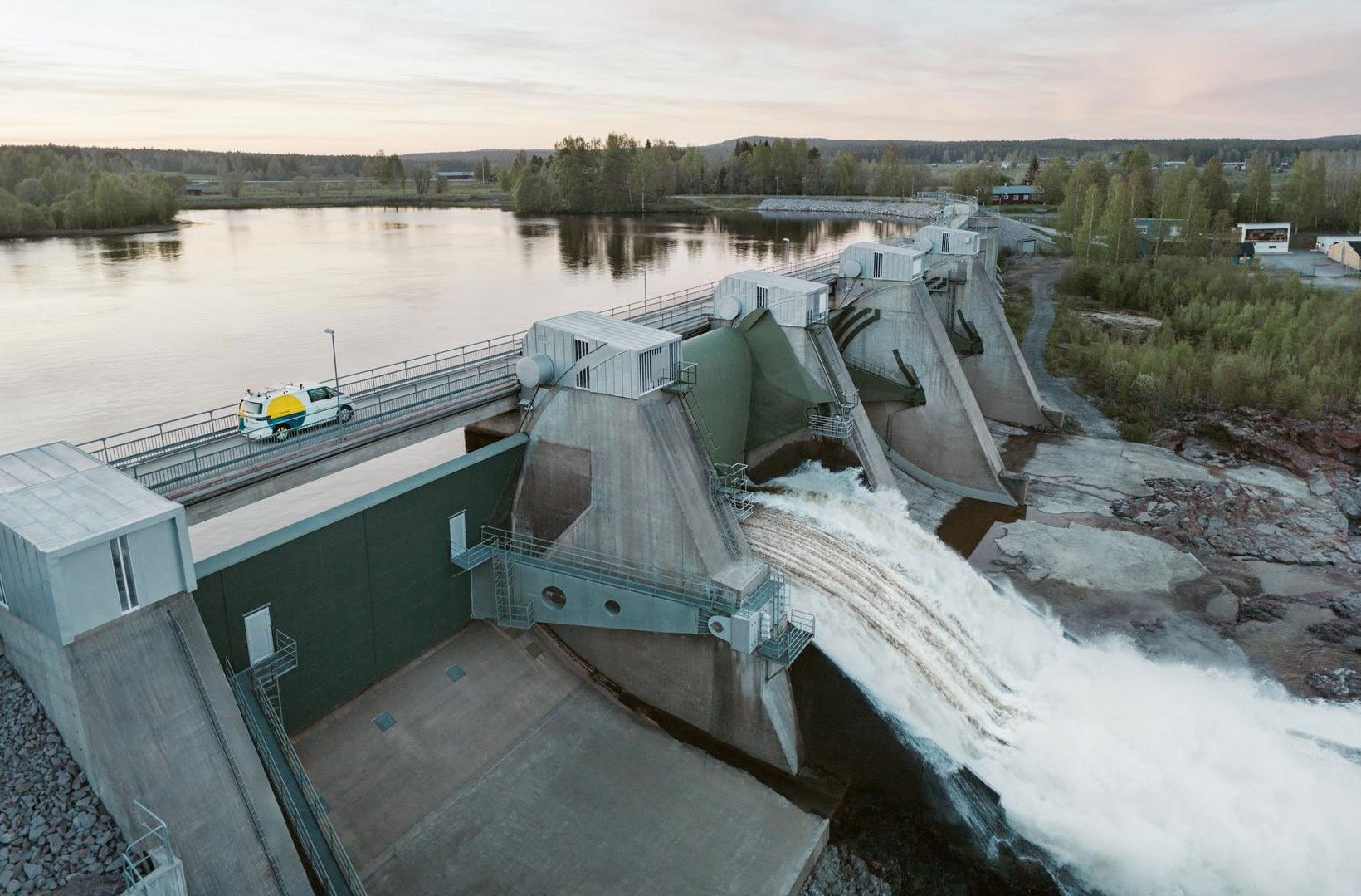 Stornorrfors vattenkraftverk. En stor damm med strömmande vatten och ett fordon i närheten, beläget vid en flod.
