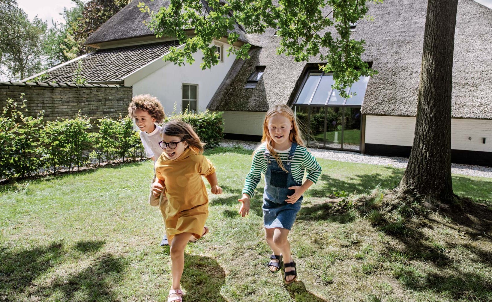 Tre barn som springer i en trädgård