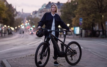 Kvinna som står bredvid sin cykel på en gata i Stockholm.