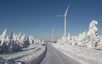 En väg och två vindkraftverk i snötäckt landskap