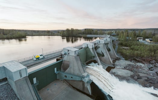 En bil från Vattenfall åker ovanför dammluckorna i ett vattenkraftverk.