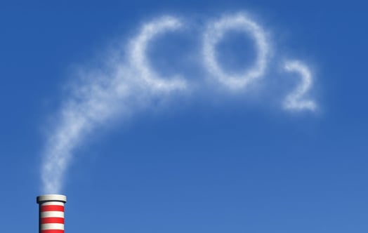 Rödvitrandig skorsten släpper ut vit rök som formar texten ”CO2” mot klarblå himmel. Rödvitrandig skorsten släpper ut vit rök som formar texten ”CO2” mot klarblå himmel.