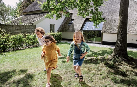 Tre barn som springer i en trädgård