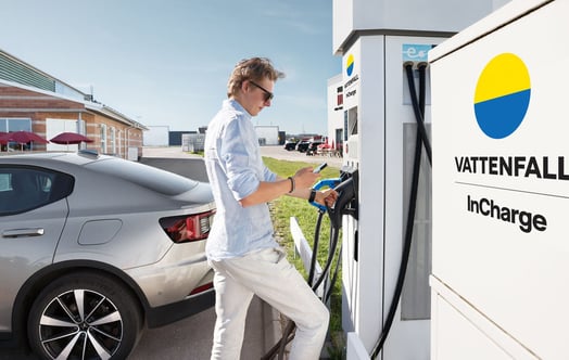 Man som laddar elbil vid laddstation