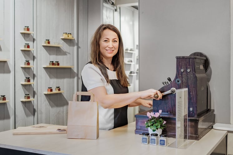 En kvinna vid en gammaldags kassaapparat i en butik En kvinna vid en gammaldags kassaapparat i en butik
