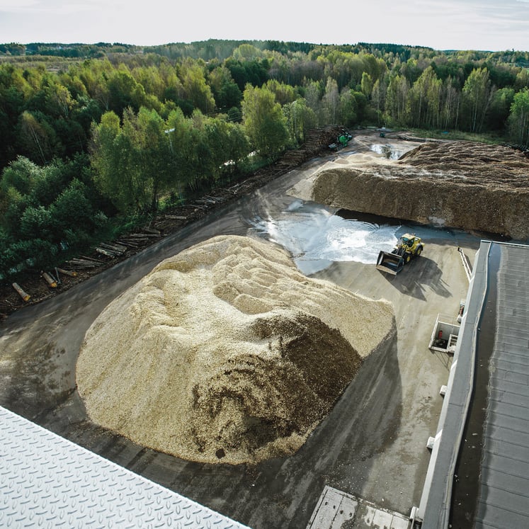 Biomassaanläggning med stora högar träflis och en hjullastare. Biomassaanläggning med stora högar träflis och en hjullastare.