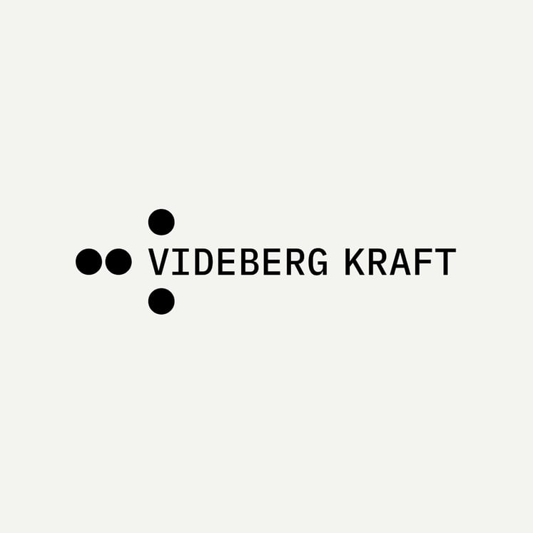 Logotyp med svart text “VIDEBERG KRAFT” med fyra svarta cirklar på beige bakgrund.