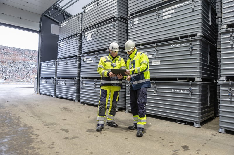 Andrej Dembek och Andreas Ahagen framför de plomberade lådorna med avfall som staplats på hög i väntan på tömning.