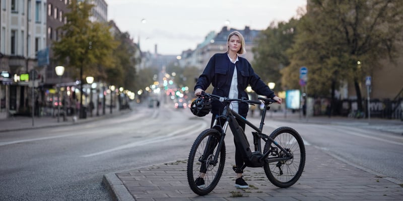 Kvinna som står bredvid sin cykel på en gata i Stockholm.