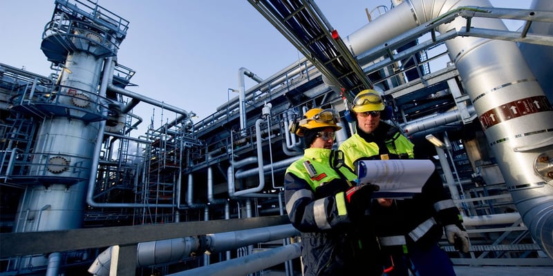 Två personer iklädda varselkläder och gula hjälmar på ett av Preems raffinaderier. Två personer iklädda varselkläder och gula hjälmar på ett av Preems raffinaderier.