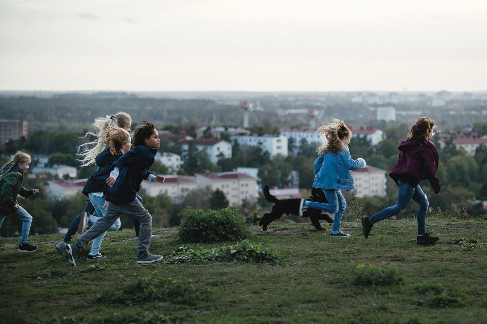 En grupp springande barn på en kulle