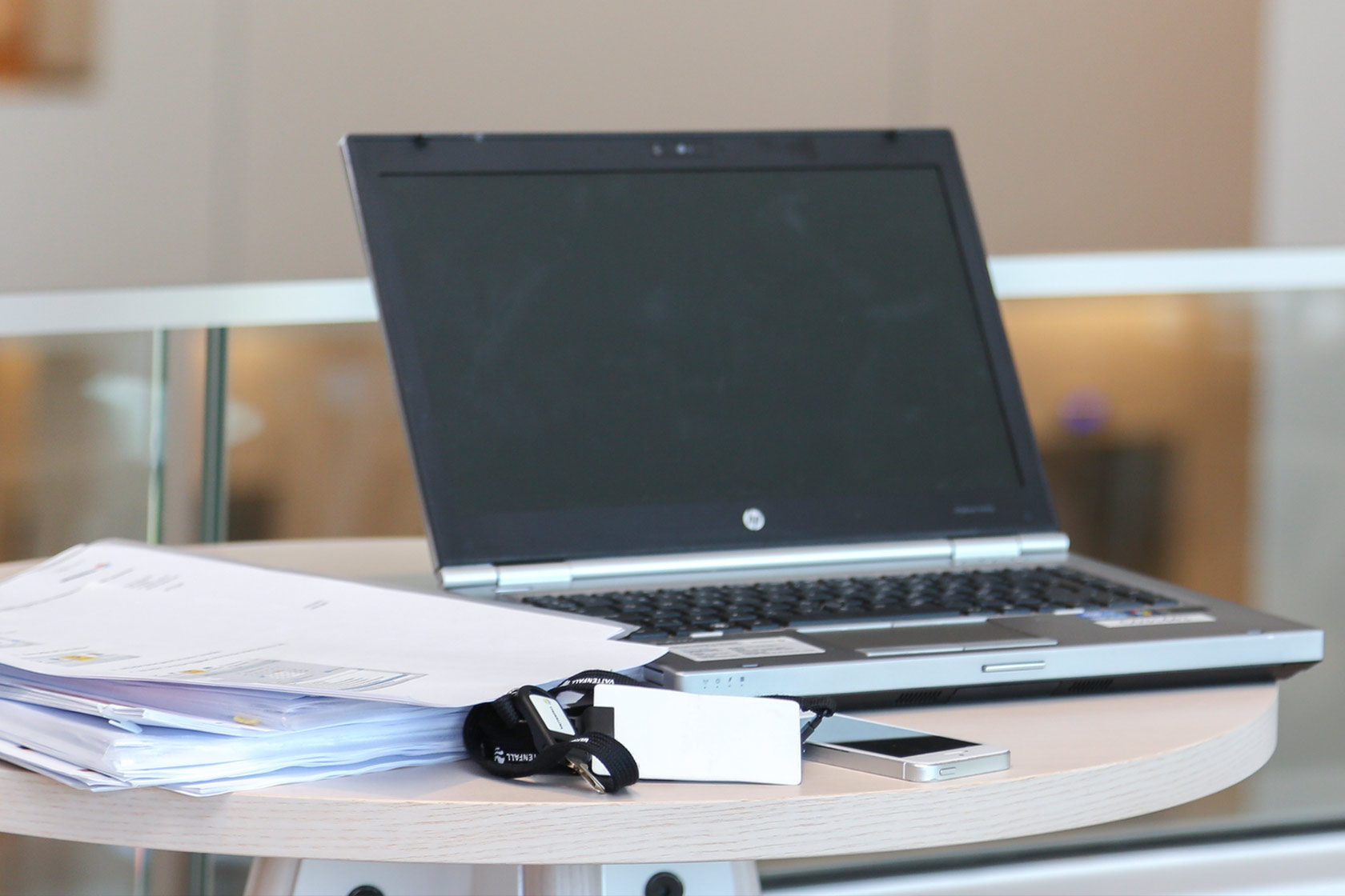 En bärbar dator bredvid en hög papper på ett bord