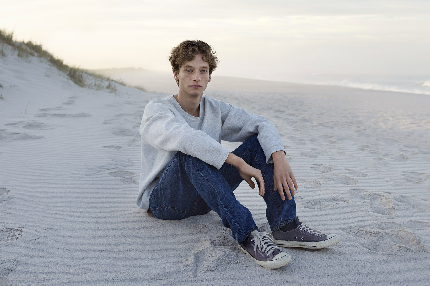 En tonårspojke som sitter på en strand